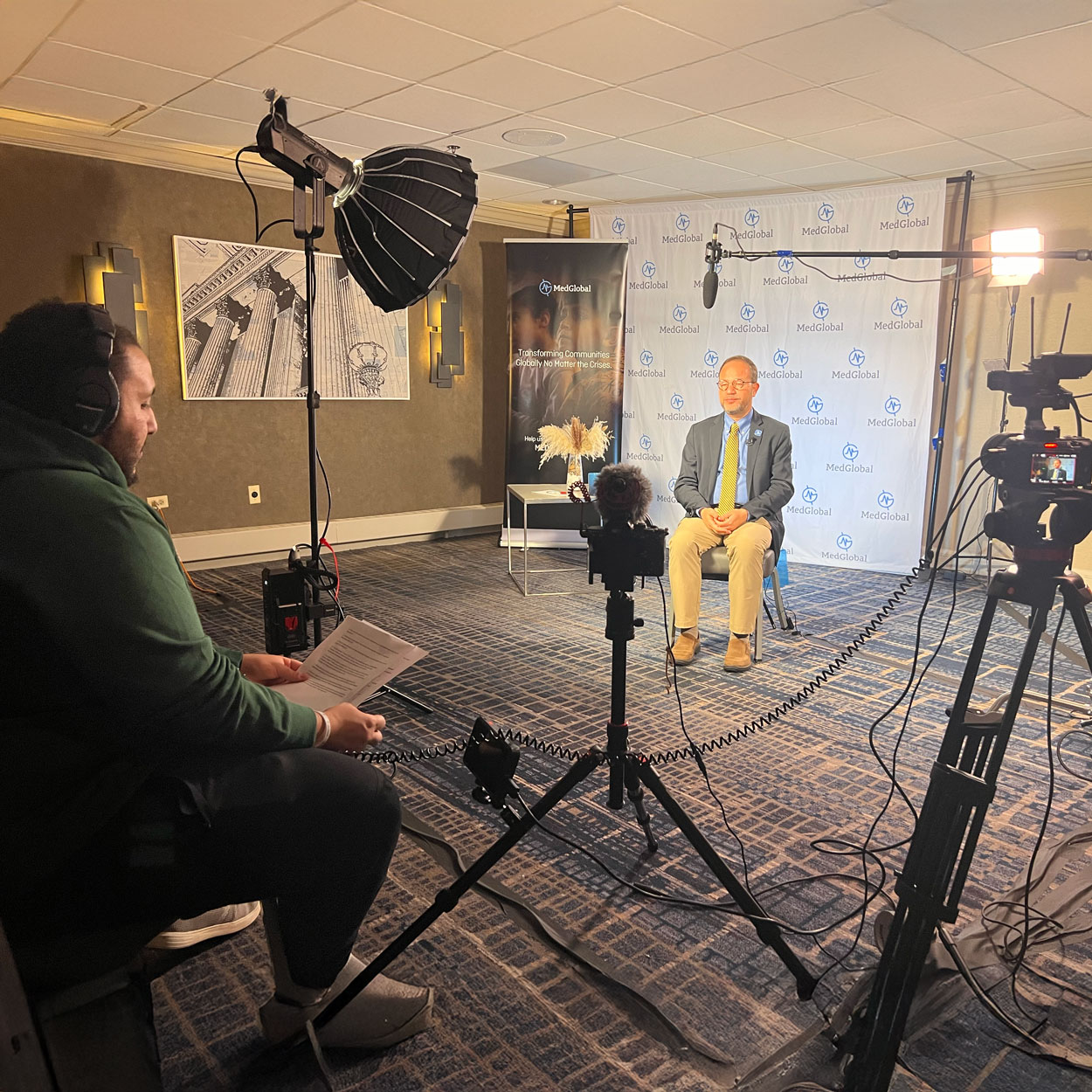 A man reading text off a paper reads questions while filming an interview