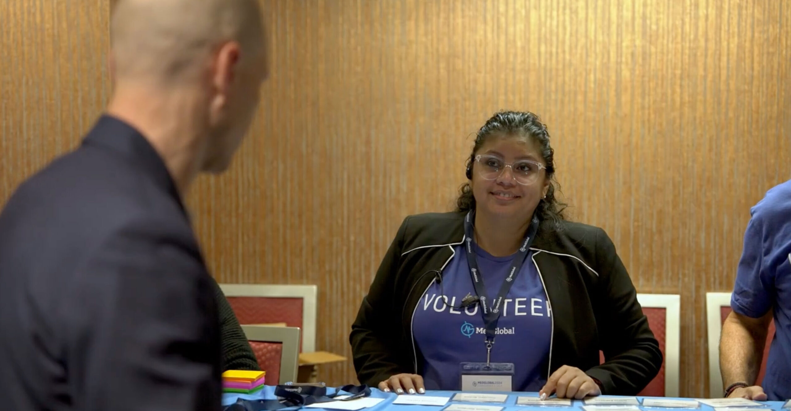 MedGlobal Volunteer behind a table helping a man